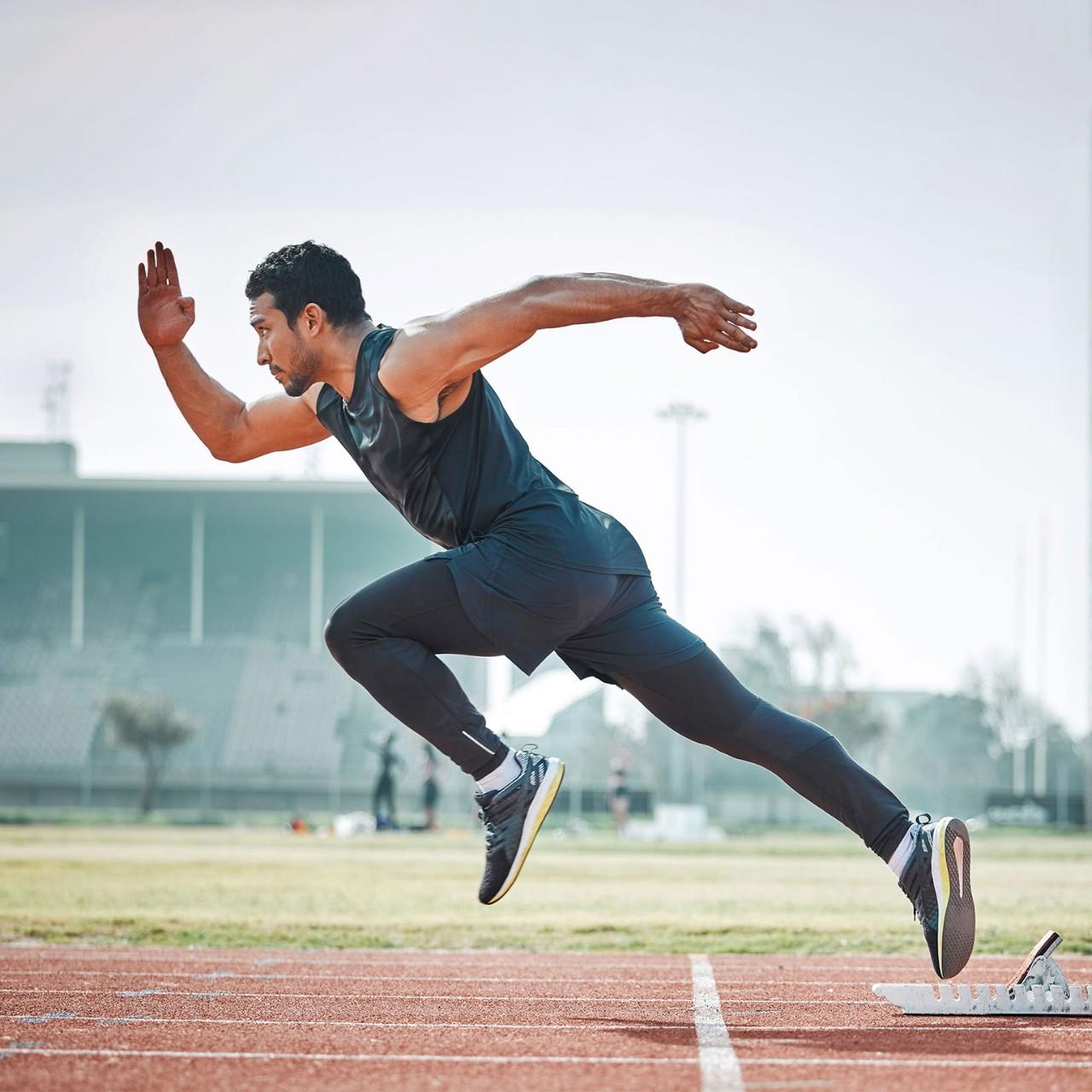 Athletic man running on arena track, sprint race training run and sports